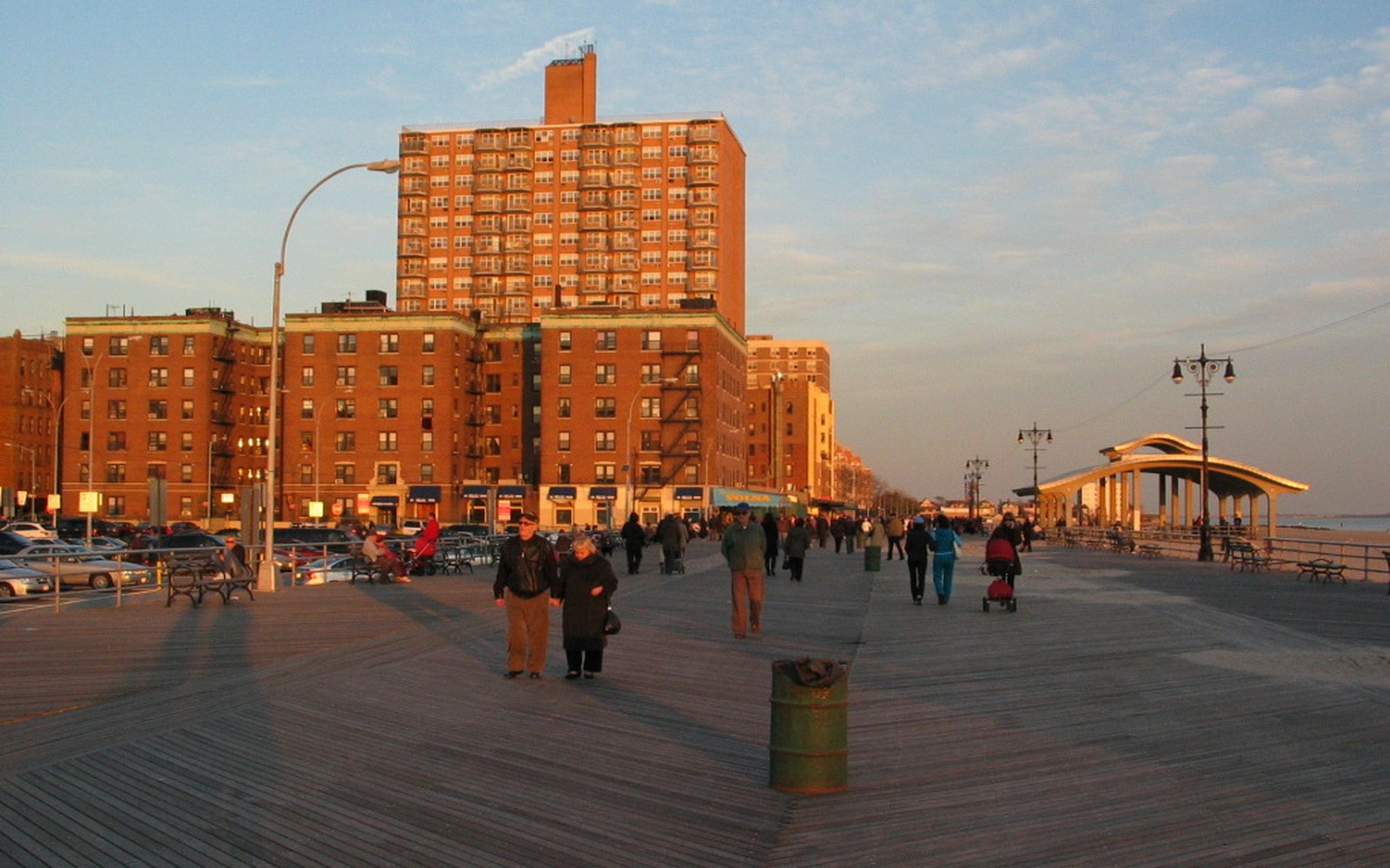 A seafront boardwalk in off-season light with adults walking
